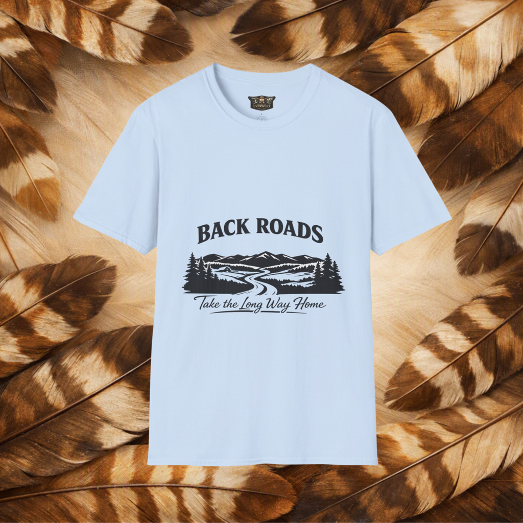 A light blue short-sleeve t-shirt with a black graphic print reading 'BACKROADS' and 'Take the Long Way Home' over a mountain and roadway scene, displayed flat against a background of brown and tan feathers.