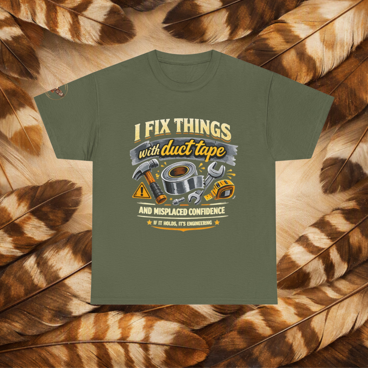 Miltary Green t-shirt with a front view graphic with tools and text that reads'I Fix Things With Duct Tape and Misplaced Confidence, If it Holds It's Engineering', laid flat on a background of cream and brown feathers.