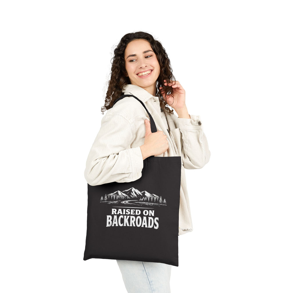Black canvas tote bag with front mountain print and Raised on Backroads lettering