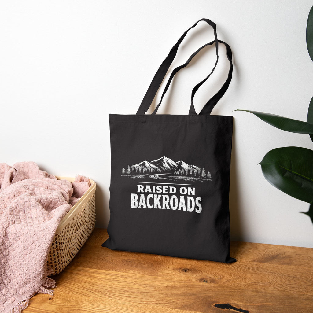 Black canvas tote bag with mountain graphic and Raised on Backroads text