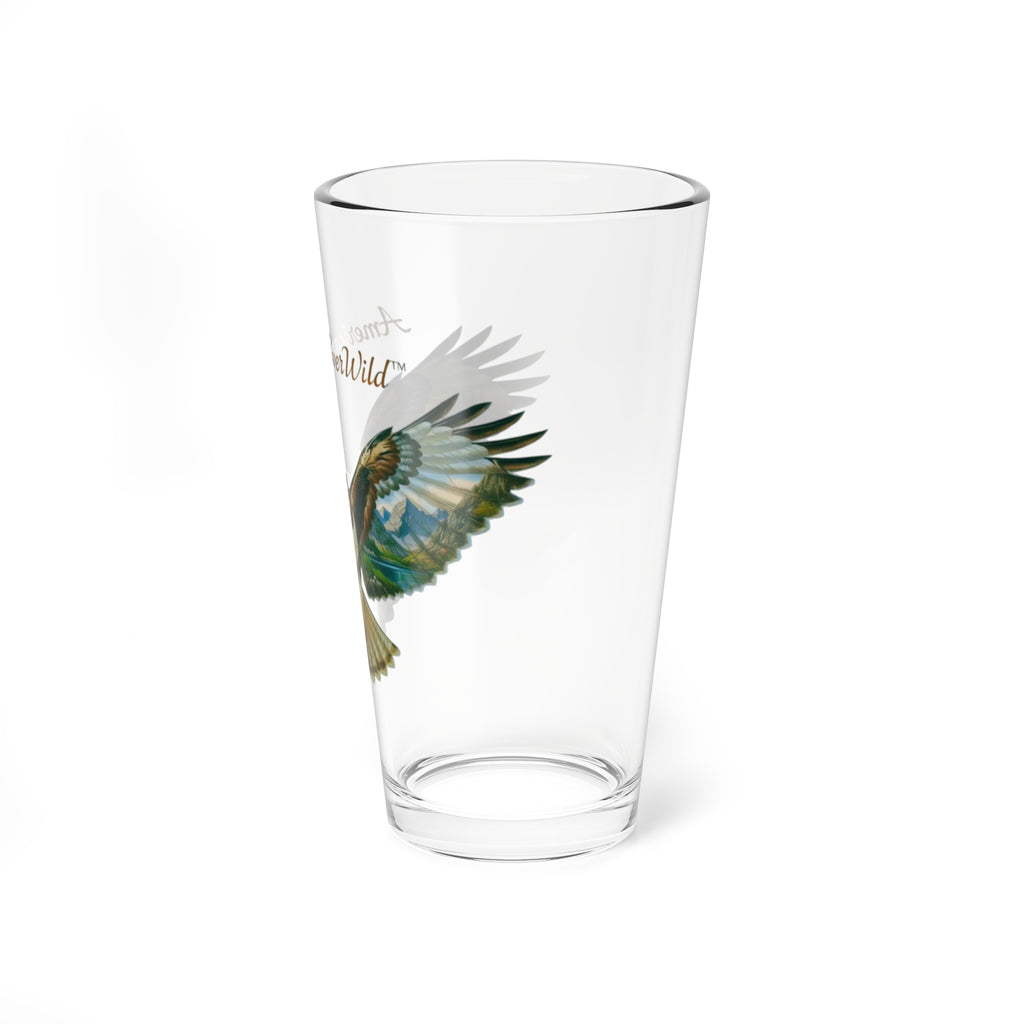 A clear glass pint glass featuring a printed graphic of a red-tailed hawk with right side of the painted wings and the text ' Wild' in brown and green tones, shown on a plain white background.