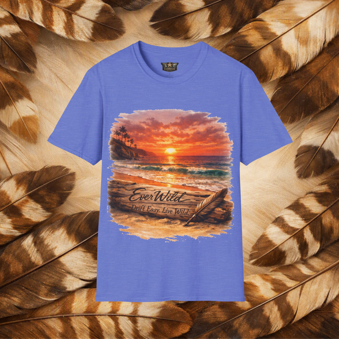 A heather royal sleeve crewneck t-shirt featuring a large graphic print of a beach sunset with the text 'EverWild Frift Easy Live Wild', displayed against a background of brown and beige feathers.