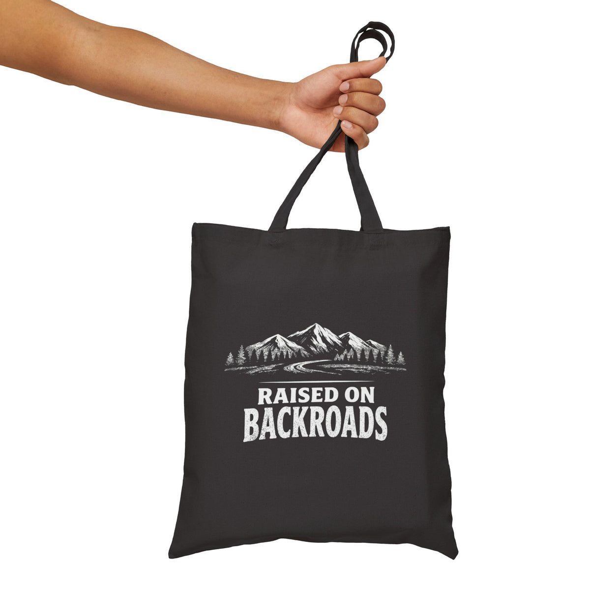 Black canvas tote bag with handles and mountain graphic with Raised on Backroads text