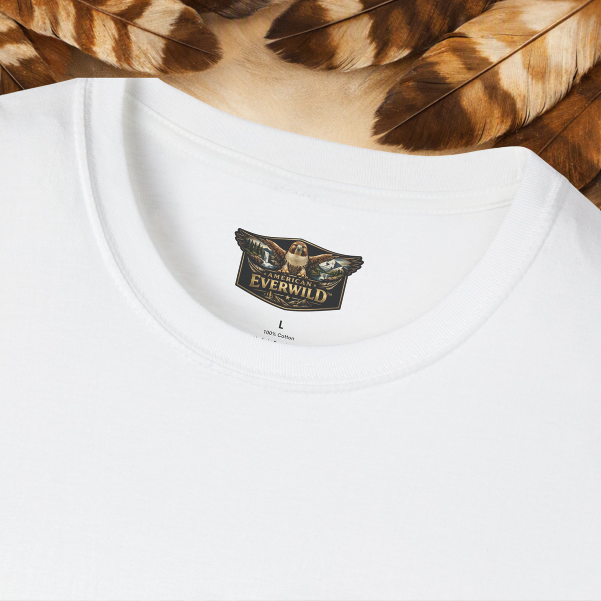 Close-up of a white crew-neck t-shirt showing the inner neck label with the '
American Everwild' brand logo and hawk with painted wings, styled with brown and tan feathers at the top.