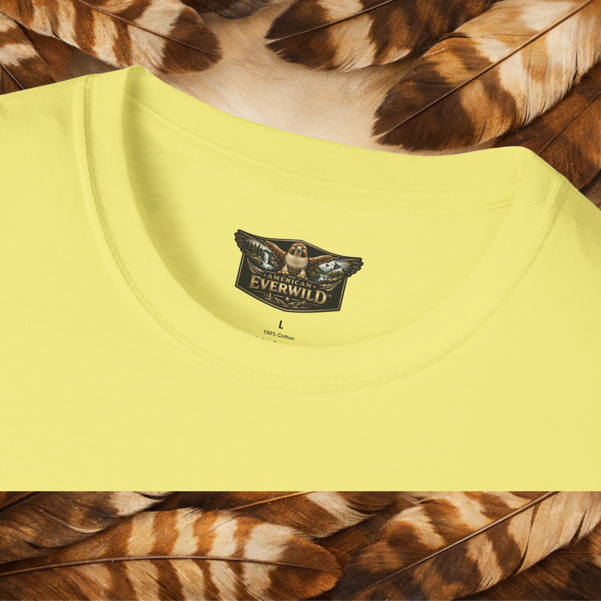 A close-up of a pale yellow t-shirt showing the inner neck label with the 'American Everwild' brand logo, styled with brown and tan feathers at the top and bottom.