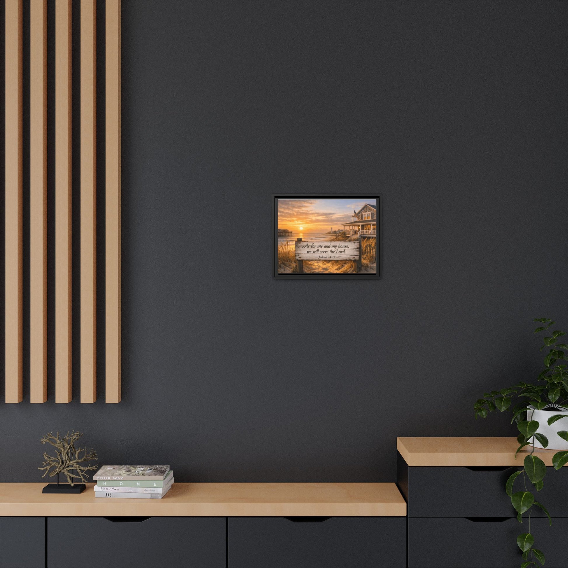 Framed coastal scripture wall art on dark wall above console with plants and decor.