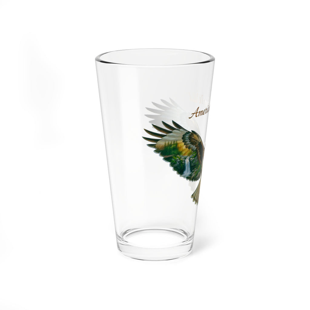A clear pint glass featuring a printed graphic of a red-tailed hawk left wing with painted feathers , alongside the partial text 'American' in brown script.