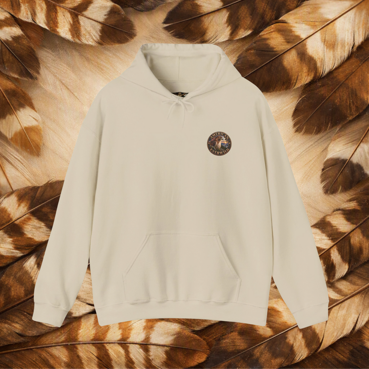 An sand-colored hooded sweatshirt with a kangaroo pocket and a small circular embroidered logo on the left chest, displayed against a background of brown and beige feathers.