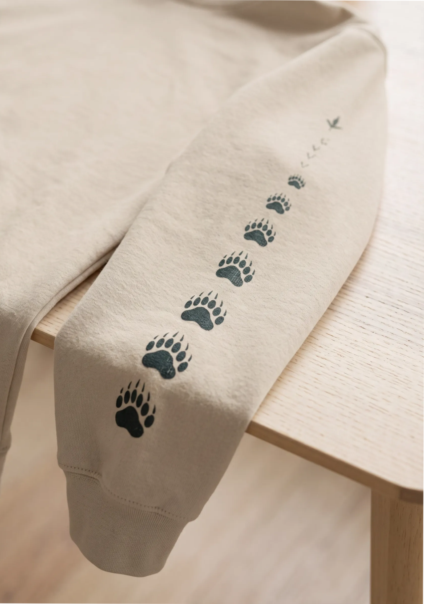 Beige hoodie sleeve with small black paw-print graphics