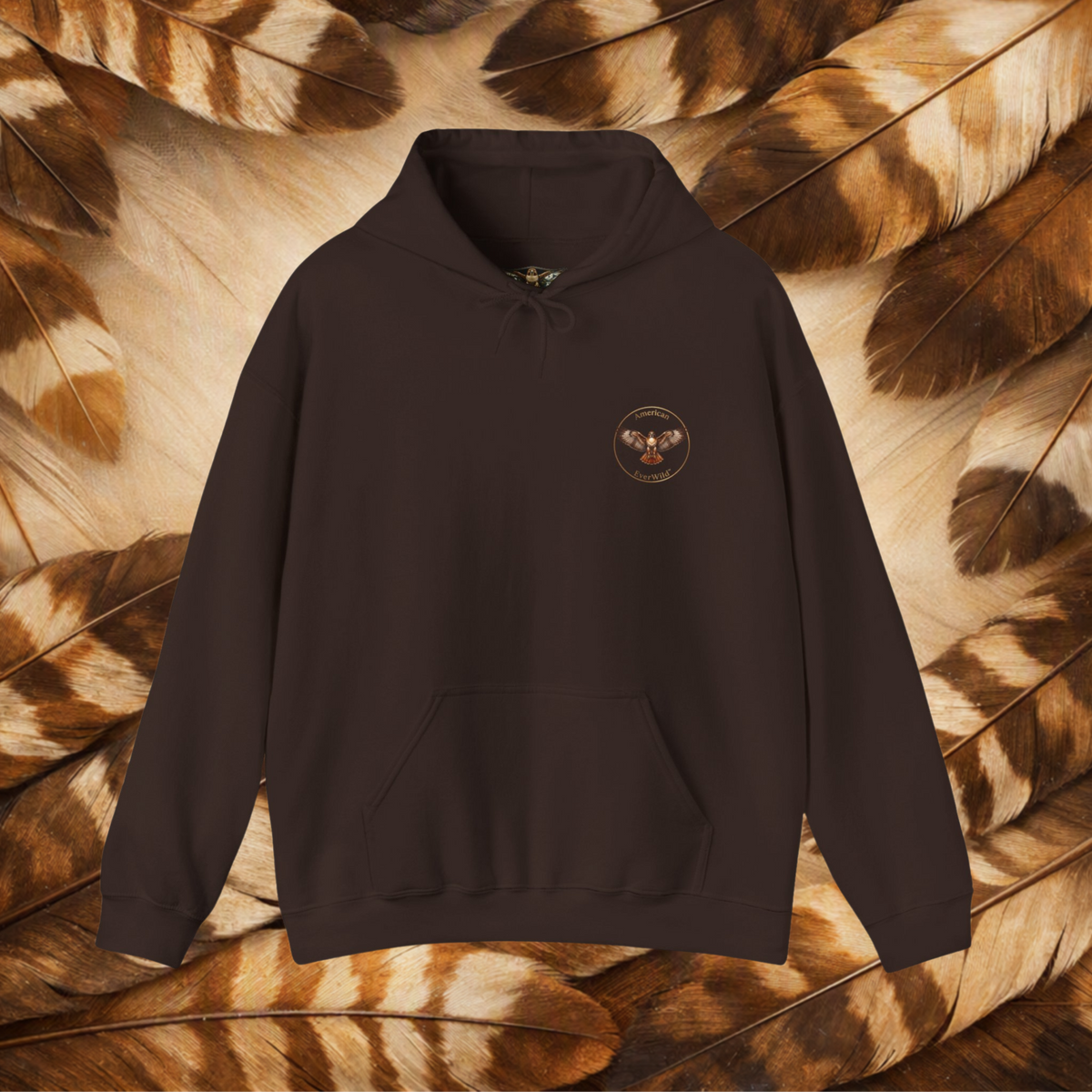 A chocolate brown pullover hoodie with a small circular hawk graphic on the left chest with the text "American Everwild." Displayed against a background of brown and beige feathers.