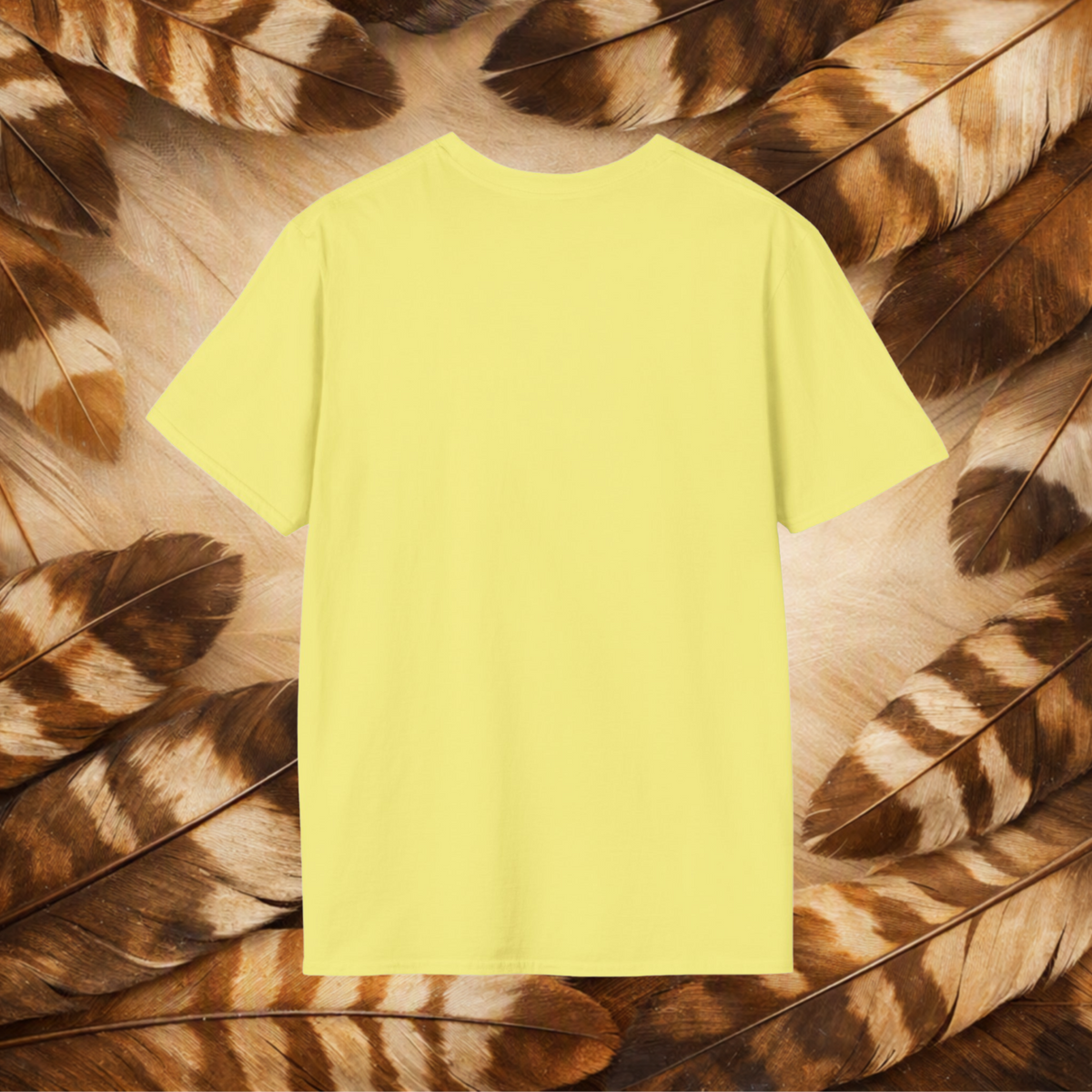 A pale yellow t-shirt back view laid flat on tan and brown feathers.