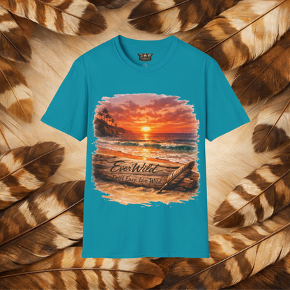 A tropical blue short-sleeve t-shirt with a large rectangular graphic print of a beach sunset scene. The graphic features the text 'EverWild Drift Easy- Live Wild' laid flat on a background of cream and brown feathers.