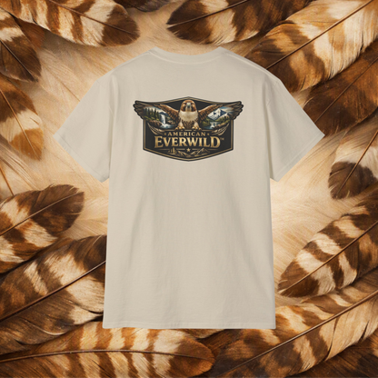 A sand-colored short-sleeve t-shirt with a large graphic on the back featuring a hawk and the text 'AMERICAN EVERWILD'. The shirt is displayed flat against a background of brown and beige feathers.