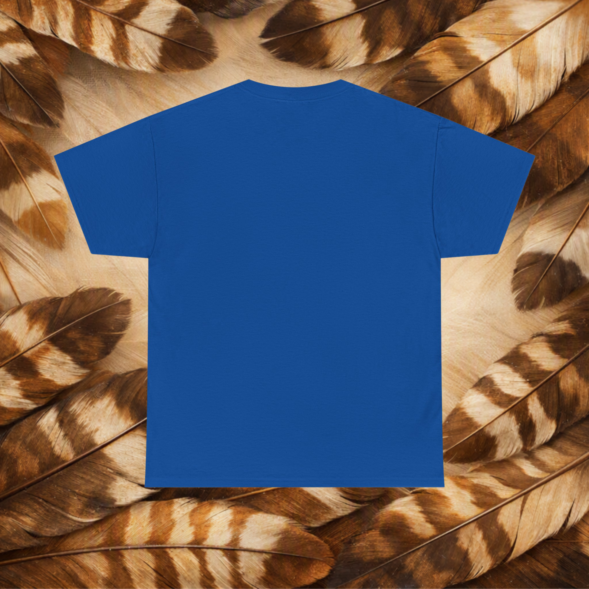 A plain royal blue short-sleeve T-shirt laid flat against a background of Hawk feathers.