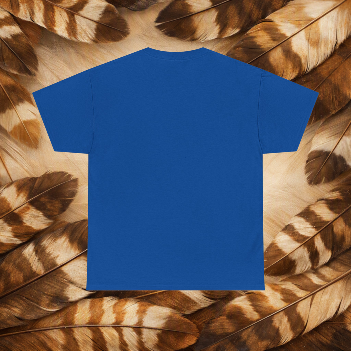 A plain royal blue short-sleeve T-shirt laid flat against a background of Hawk feathers.