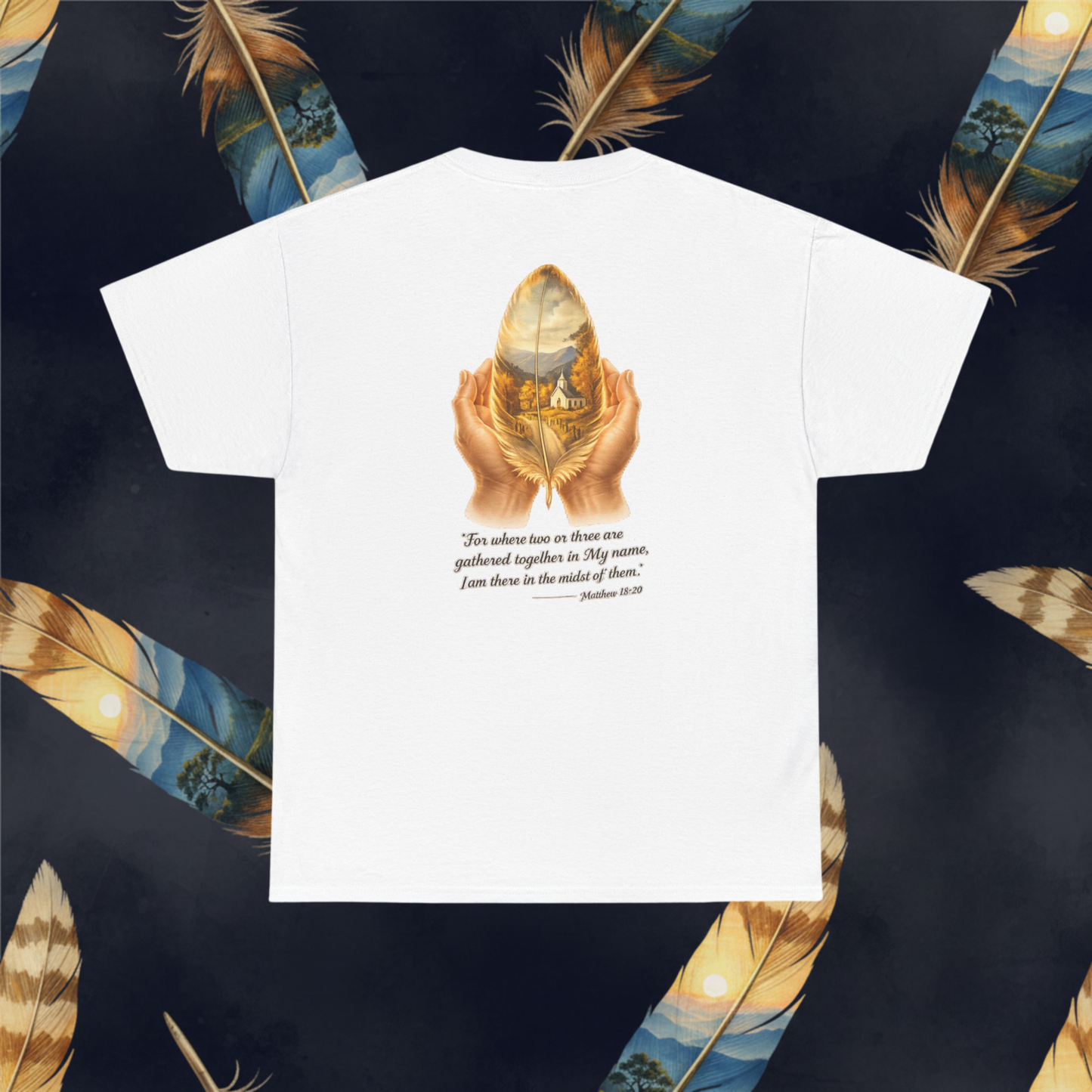 A white short-sleeve t-shirt with a graphic print on the front showing a golden feather held by two hands, with a Bible verse printed below. The t-shirt is displayed flat against a dark background decorated with large golden and blue feathers.