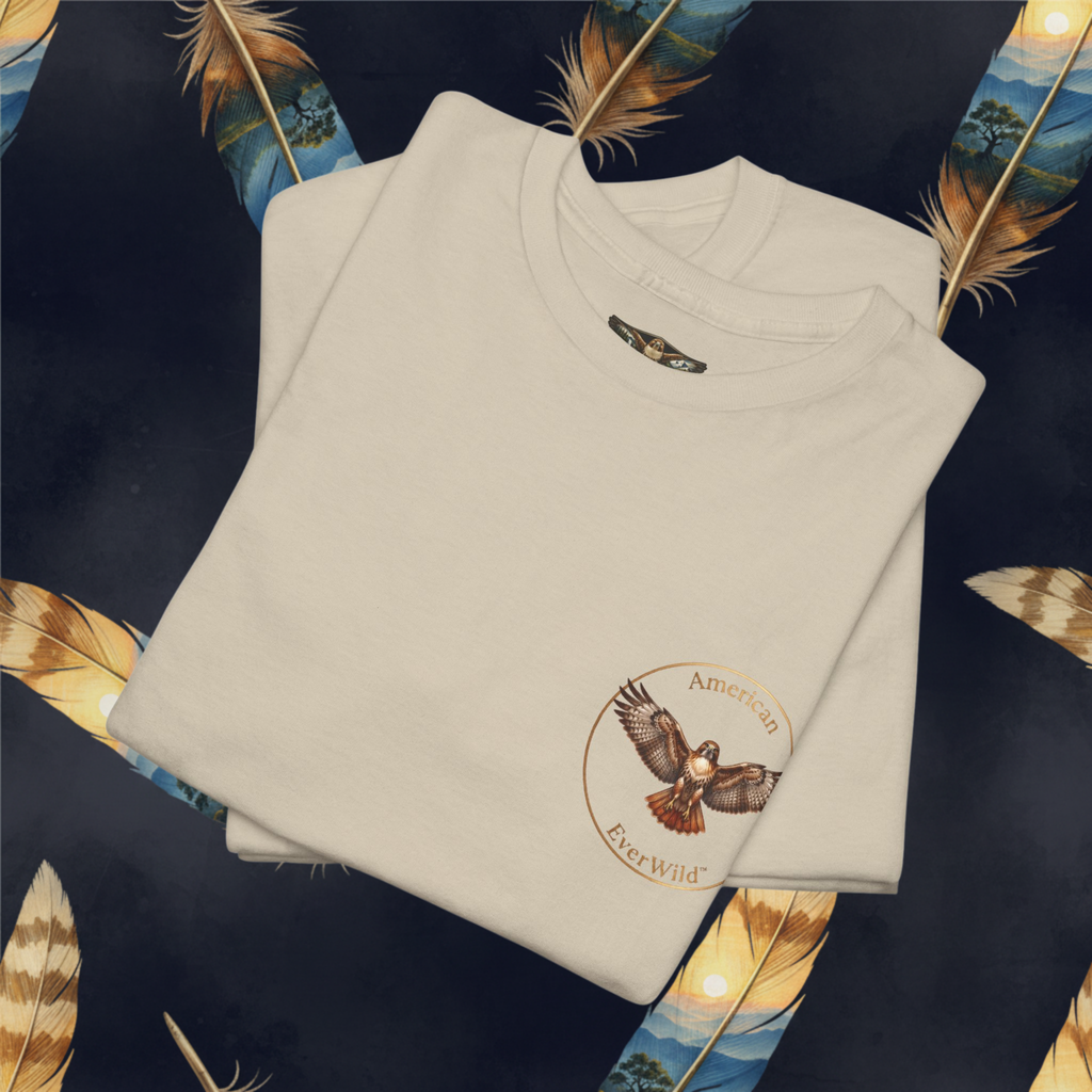 A folded cream-colored t-shirt with a circular graphic on the left chest featuring a bald eagle and the text 'American EverWild', presented on a dark background decorated with feathers.