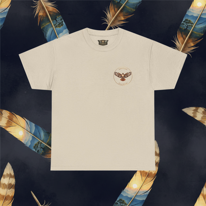 A sand color short-sleeve crewneck t-shirt with a circular embroidered hawk graphic on the left chest and text "American EverWild", displayed flat against a dark background decorated with colorful feathers.