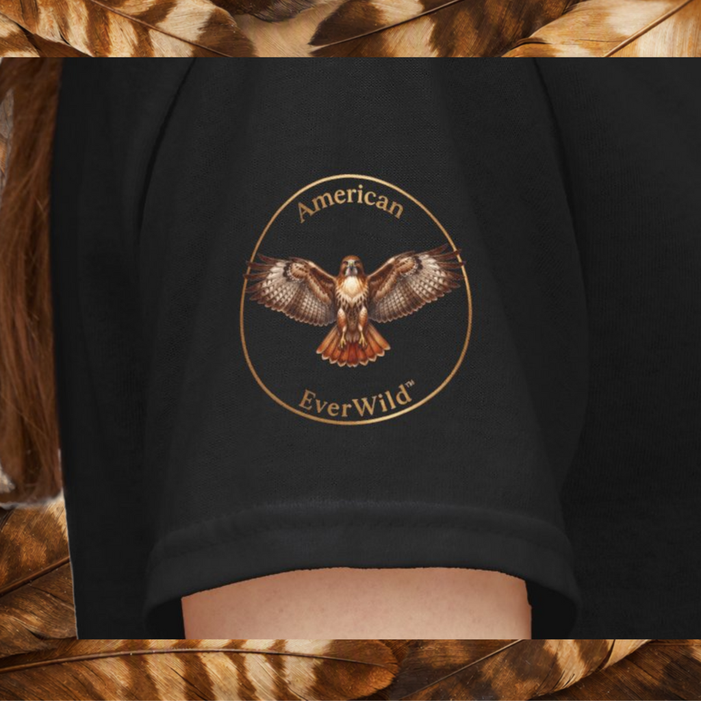 A close-up of a black sleeve featuring a circular graphic of a hawk with the text 'American EverWild' in gold, shown on a model on a back ground of brown and tan feathers.
