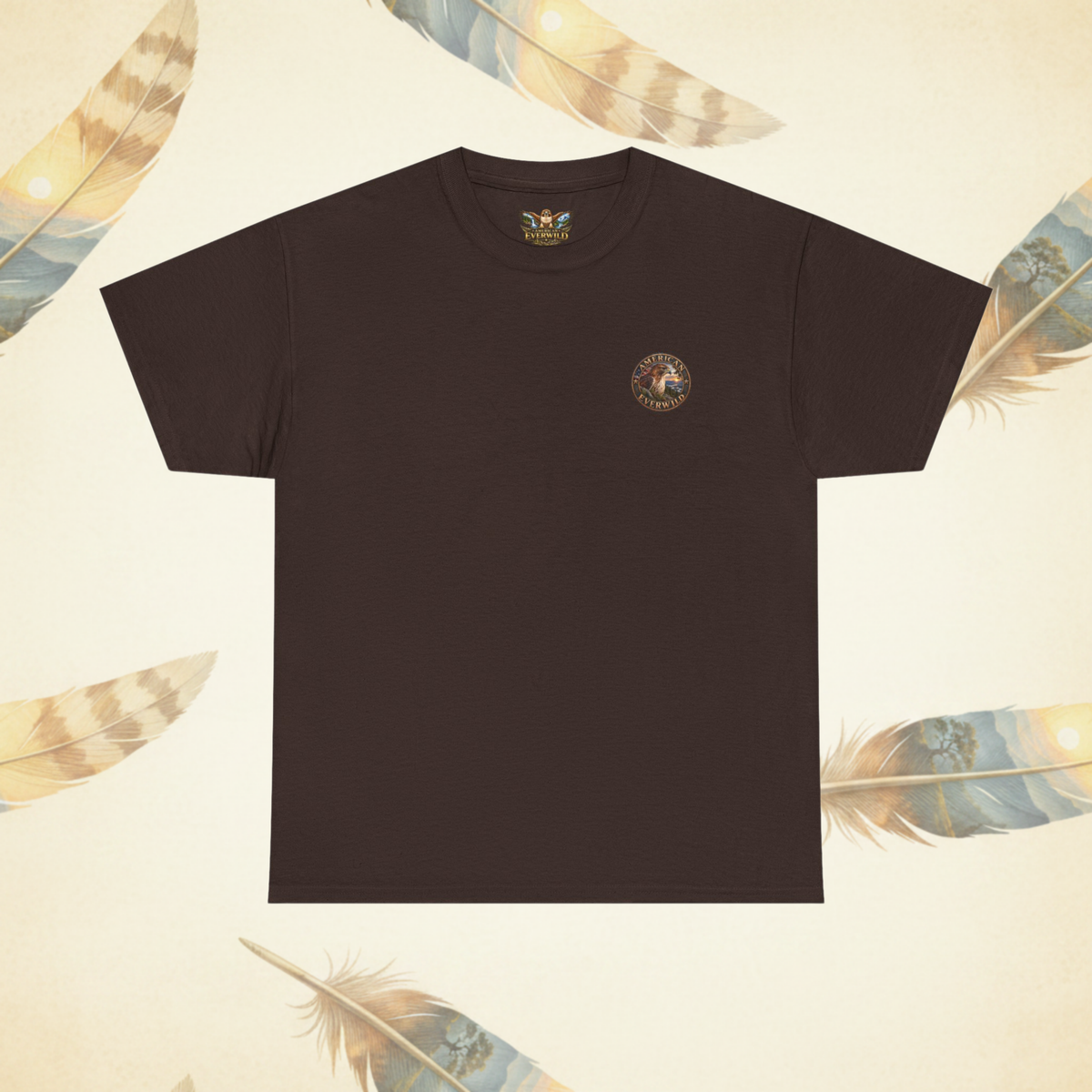 A dark brown short-sleeve crewneck t-shirt with a small circular multicolor graphic on the left chest, displayed flat against a cream-colored background decorated with feather illustrations.