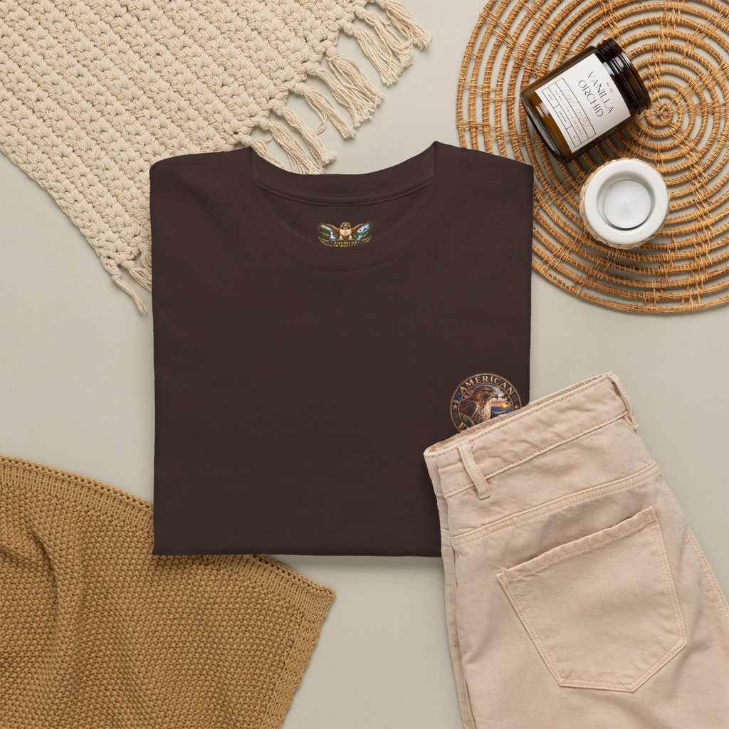 Brown t-shirt with a "American EverWild" logo design on a neutral surface with beige pants and decorative items.