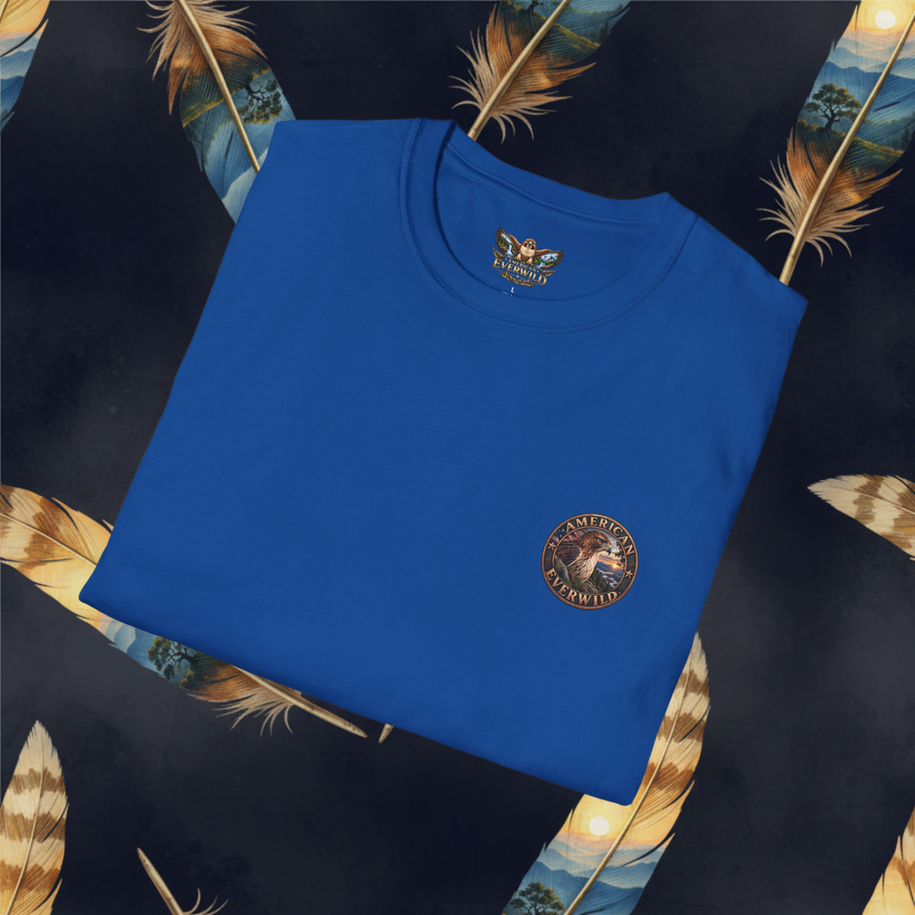 A folded royal blue t-shirt with a circular embroidered logo on the left chest, displayed on a dark patterned background with decorative feathers.