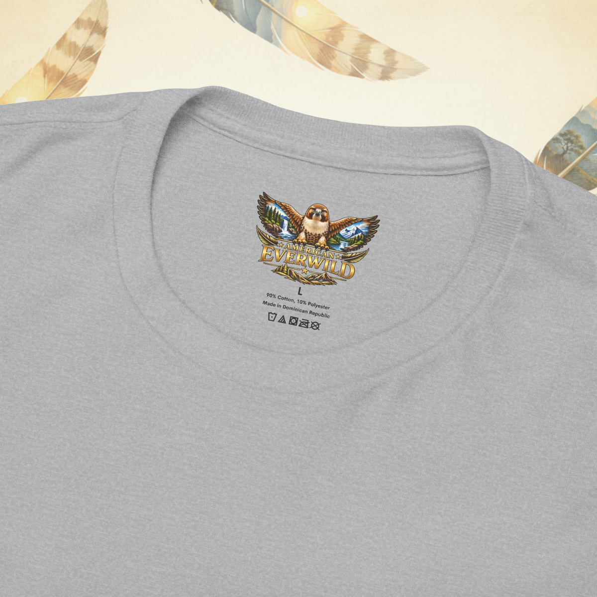 Close-up of a sport gray crewneck t-shirt featuring a colorful graphic print of the American EverWild logo inside the collar. The graphic depicts an hawk with spread painted wings and American EverWild written below it.