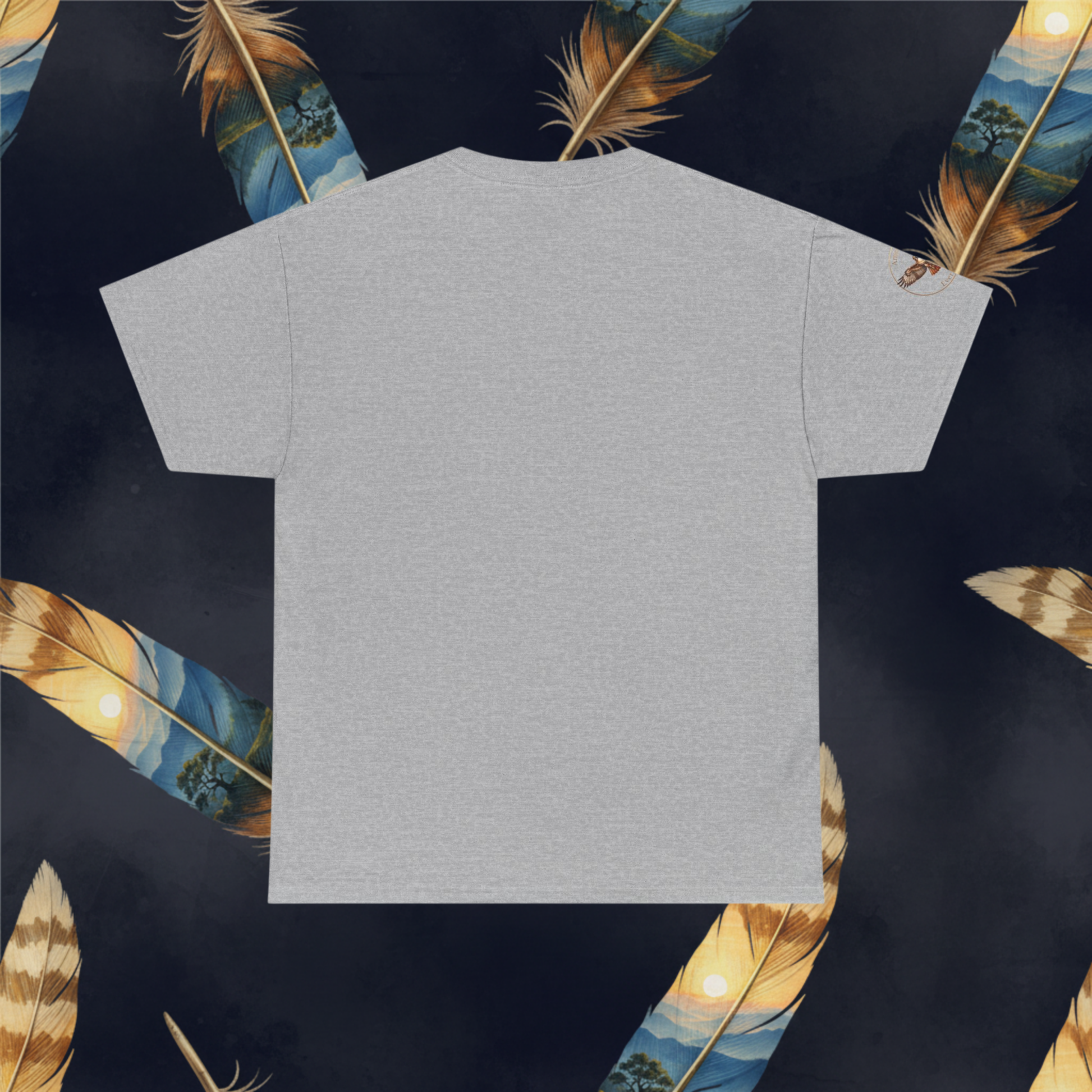 A light gray short-sleeve t-shirt is laid flat against a dark navy background decorated with illustrated feathers.