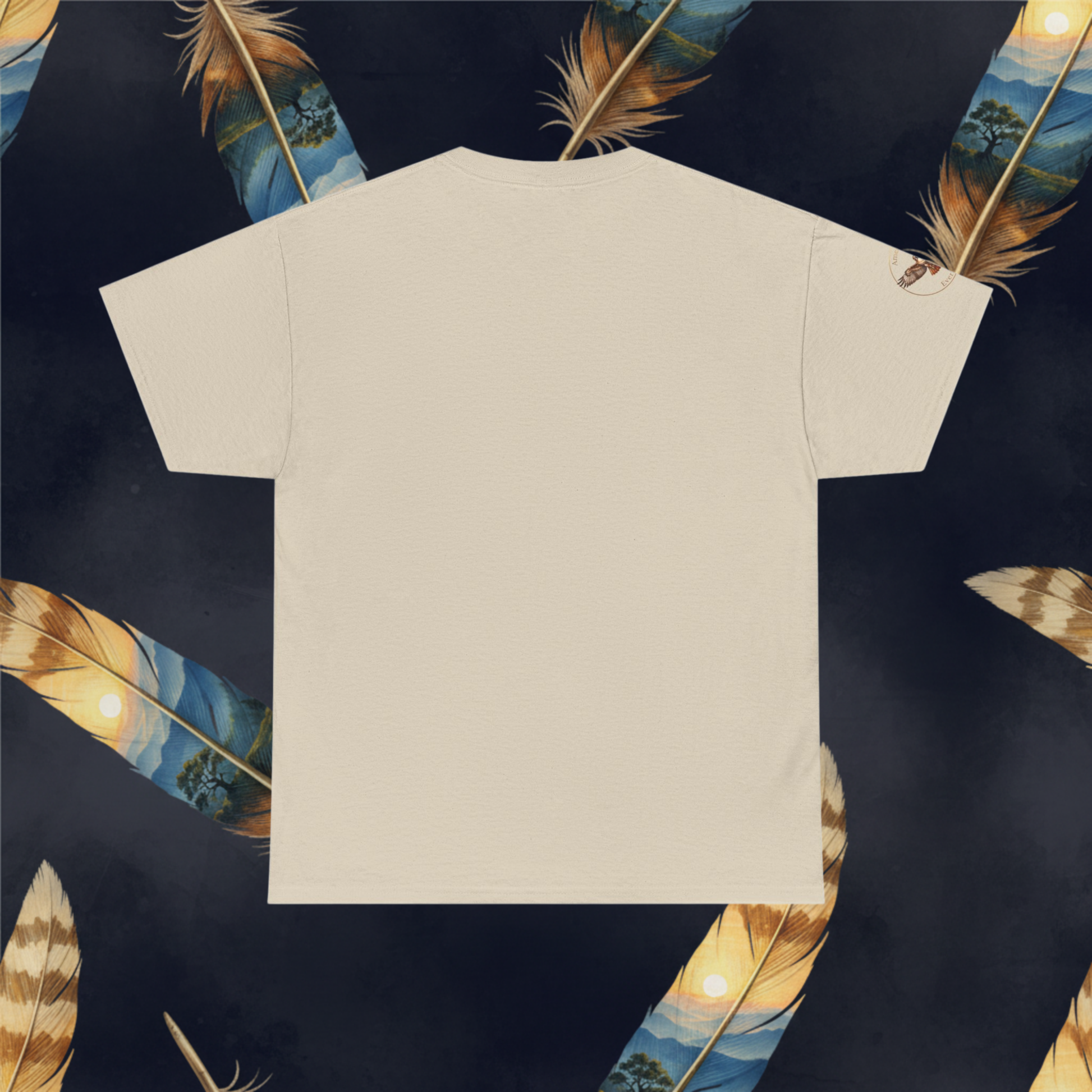 A sand colored short-sleeve t-shirt shown from the back, laid flat against a dark navy background decorated with illustrated feathers.