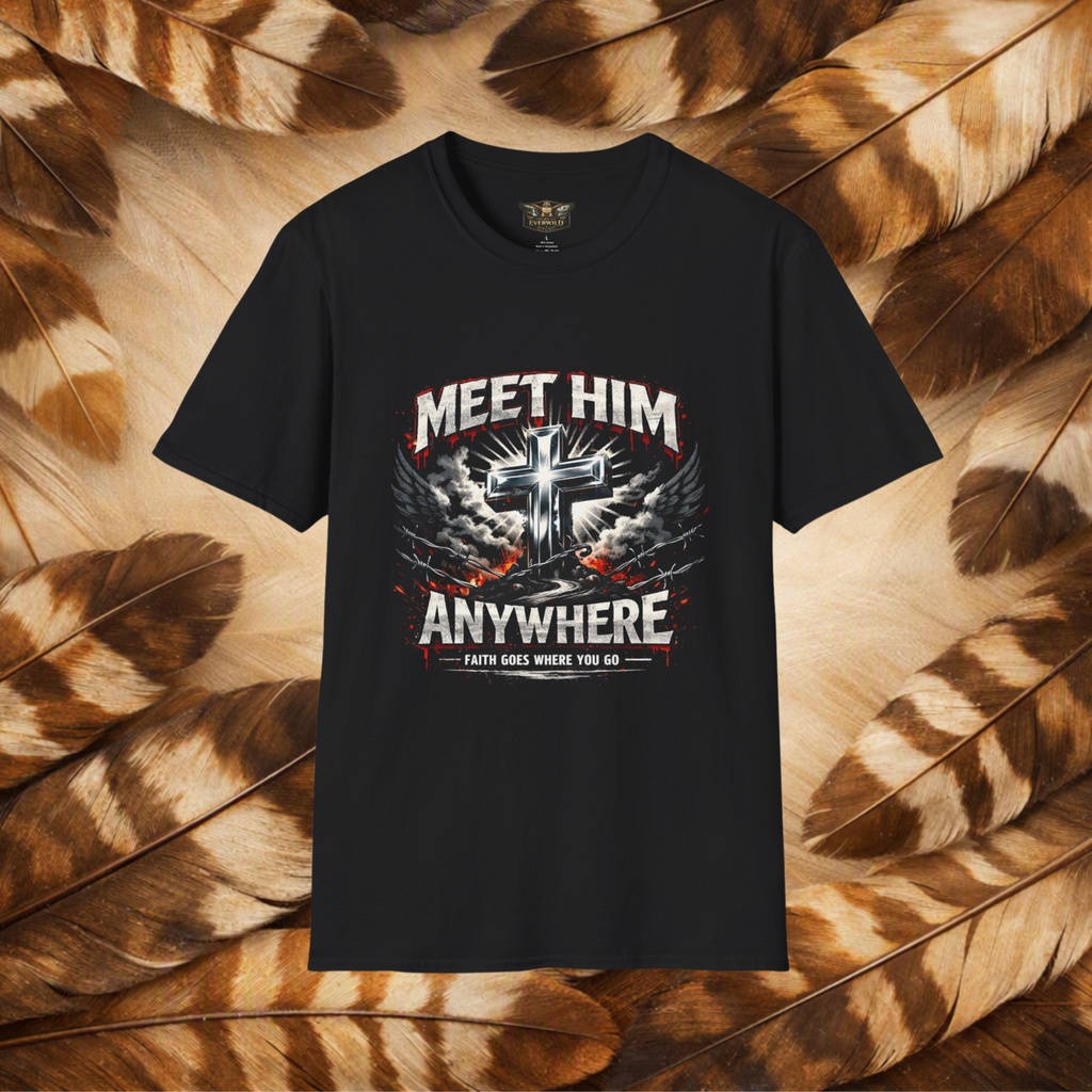 A black short-sleeve graphic t-shirt displayed flat against a background of brown and beige feathers. The shirt features a large front graphic with a metallic silver cross, white and red text reading 'MEET HIM ANYWHERE', and a banner that says 'FAITH GOES WHERE YOU GO'.