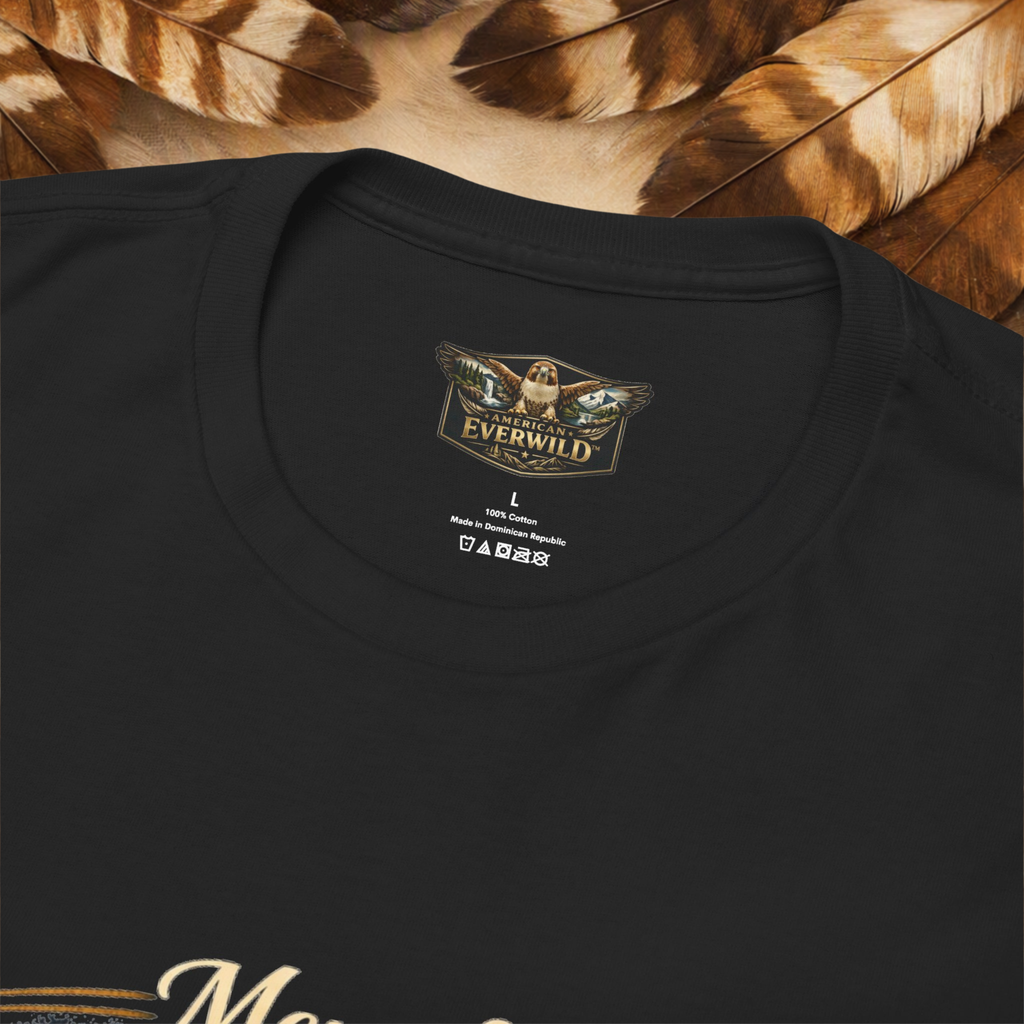 Close-up of a black crewneck t-shirt showing the inner neck label with 'The Everwild' logo, set against a background of brown and beige feathers.