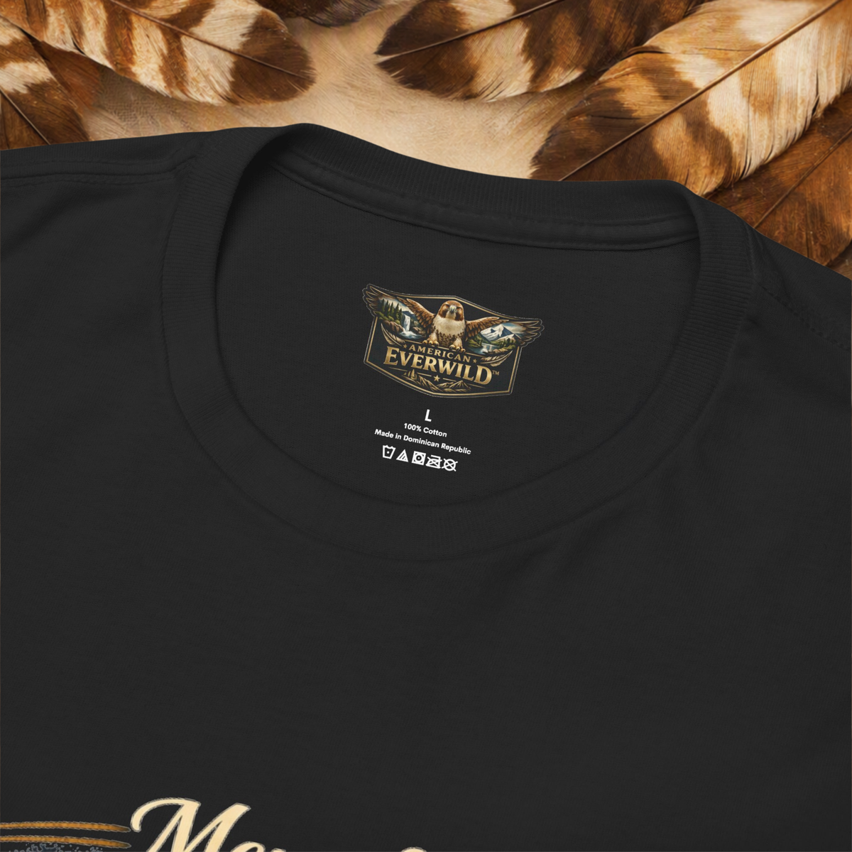 Close-up of a black crewneck t-shirt showing the inner neck label with 'The Everwild' logo, set against a background of brown and beige feathers.