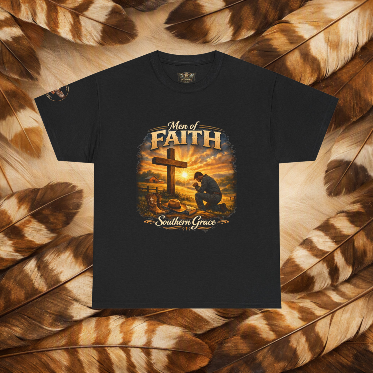 A black short-sleeve graphic t-shirt featuring a 'Men of Faith Southern Grace' Christian print with a cross and kneeling figure, displayed flat against a background of brown and beige feathers.
