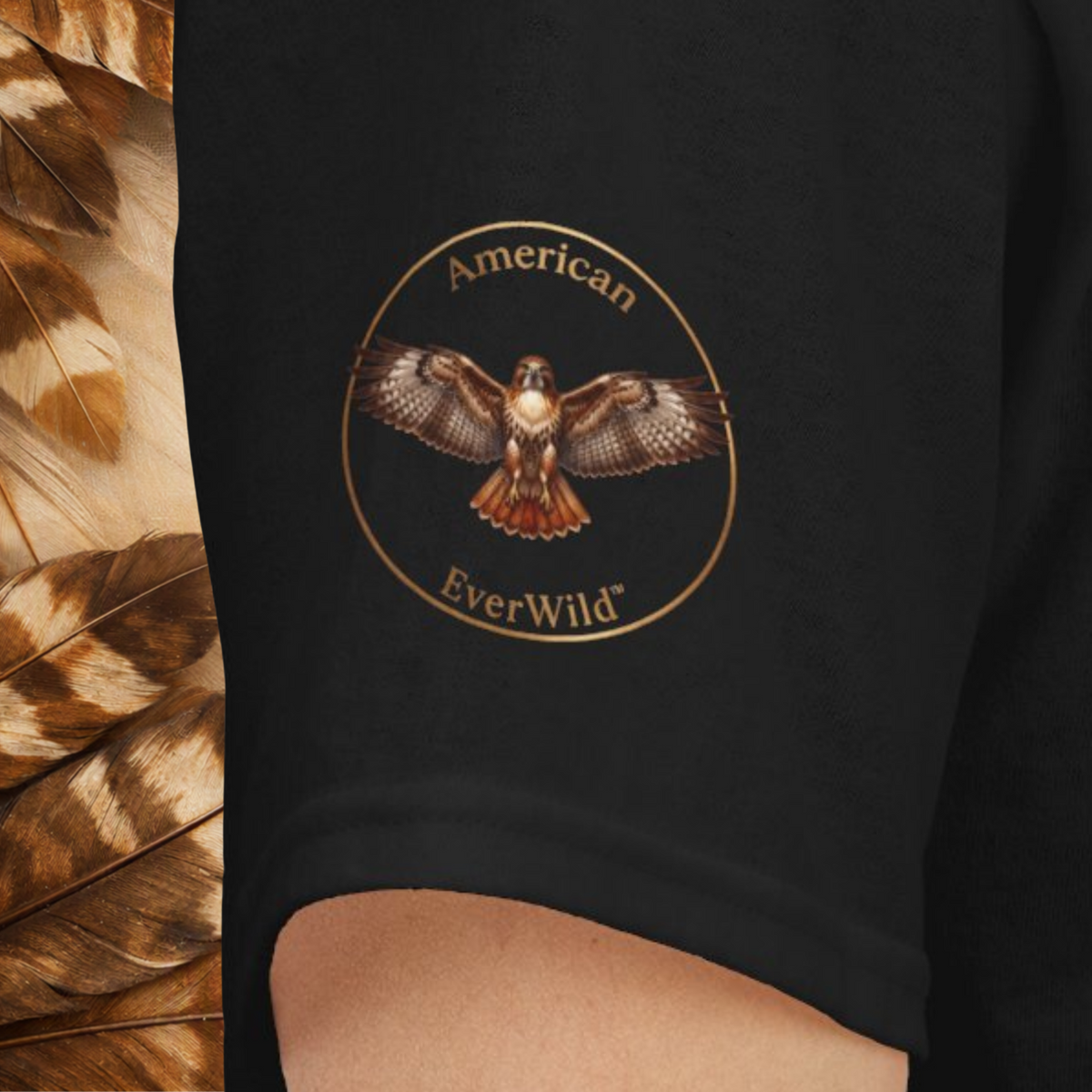 Close-up of a sleeve featuring a circular graphic with a hawk and the words 'American EverWild' in gold-toned lettering. 