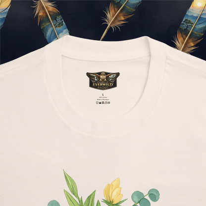 A cream colored short-sleeve t-shirt with a graphic print on the front showing the American EverWild hawk logo, with Jesus floral print below. The t-shirt is displayed flat against a dark background decorated with large golden feathers.